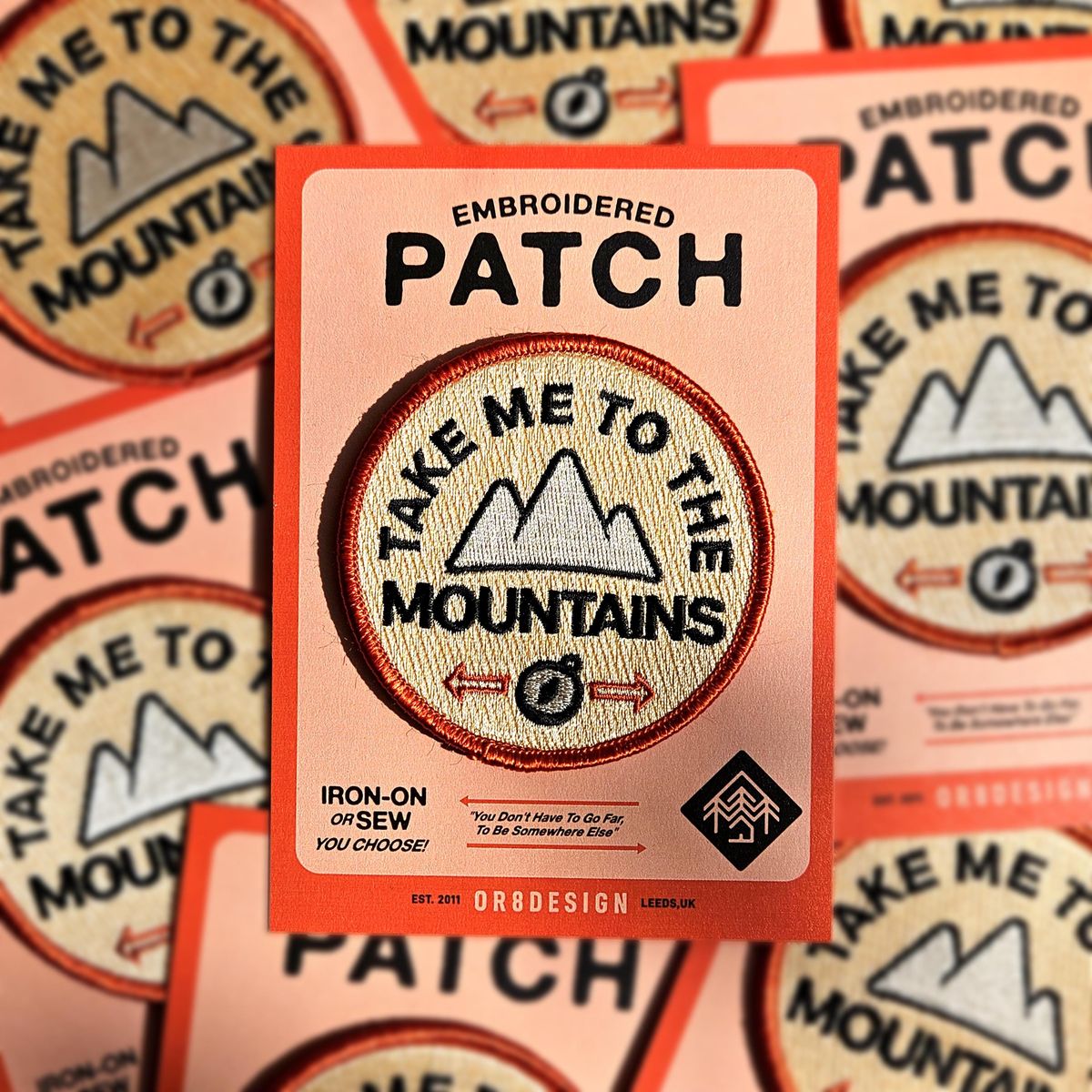 Custom embroidered patch with bold logo design on orange fabric background