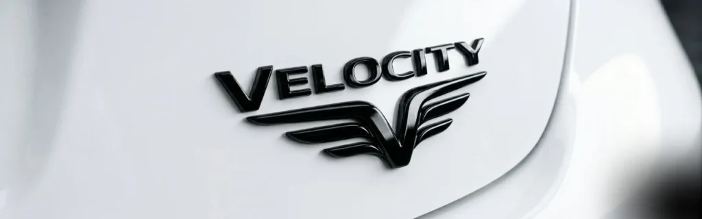 Gloss black car emblem on white paint — high contrast badge detail